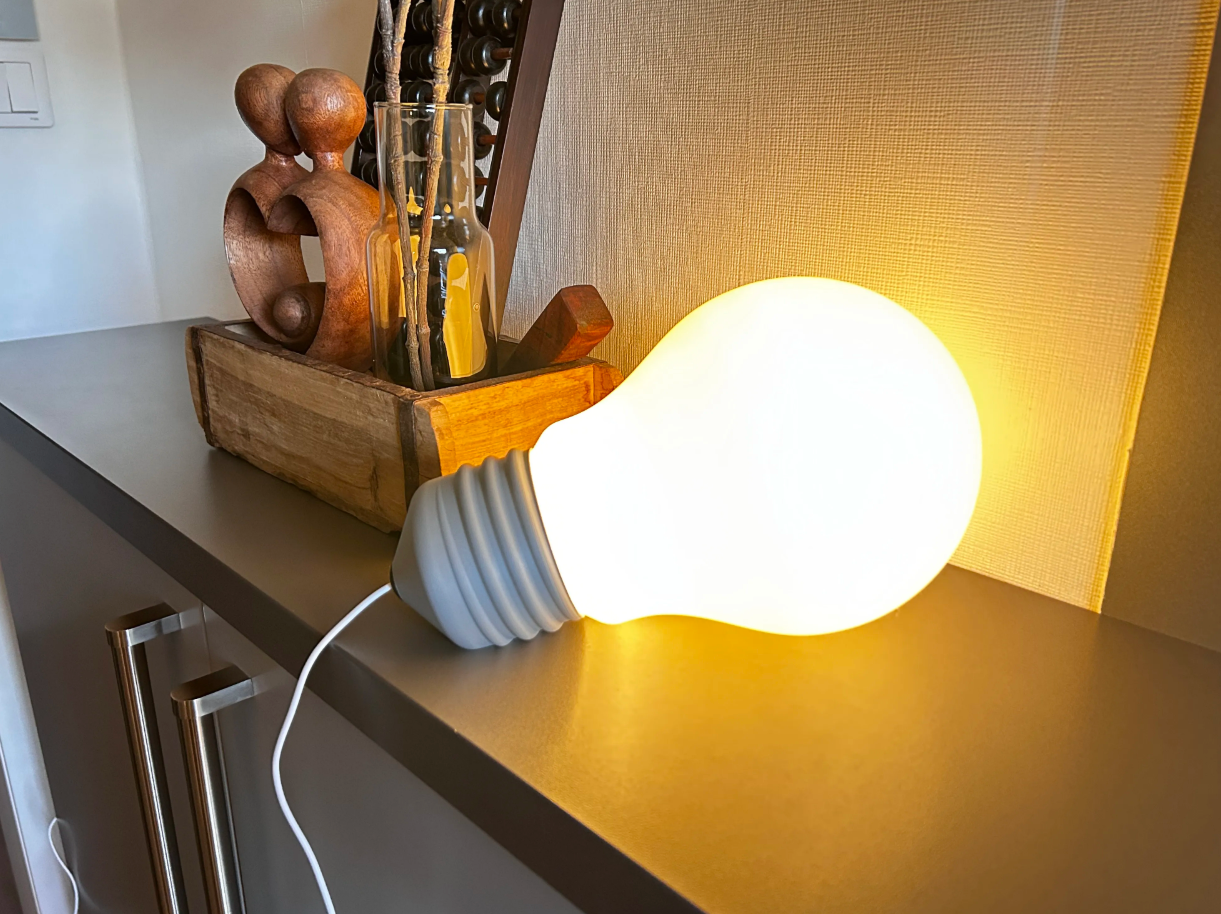 Oversized light bulb novelty lamp glowing warm on a shelf